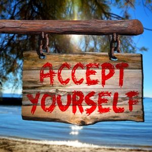 Wooden sign in front of lake "Accept Yourself"